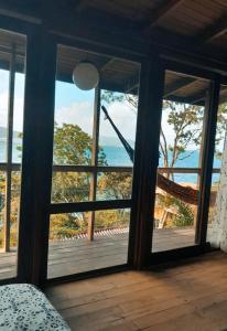 a bedroom with a view of the ocean through windows at Nirvana Ecolodge - Private accomodations in the beach side of Atlantic forest in Florianópolis