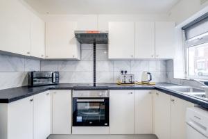 una cocina blanca con armarios y electrodomésticos blancos en Cosy 3 Bedrooms House with a Driveway close to Coventry Town Centre and University, en Coventry