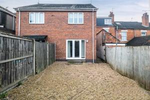 a brick house with a wooden fence and a yard at Cosy 3 Bedrooms House with a Driveway close to Coventry Town Centre and University in Coventry