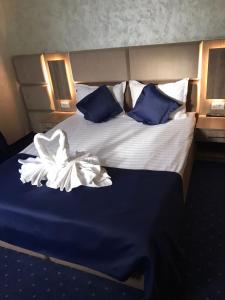 Cama grande con sábanas y almohadas azules y blancas en Le Mer, en Afumaţi