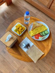 a wooden table with a plate of breakfast food on it at Besakih Homestay & Villa in Besakih