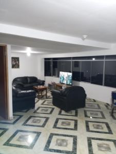 una sala de estar con 2 sofás negros y una alfombra en HuillcaNina, en Urubamba