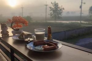 una mesa con dos platos de perritos calientes y una bebida en Kitchaview Villa, en Chiang Rai