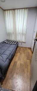 um quarto com uma cama, uma janela e um piso de madeira em Choco Residence em Seul