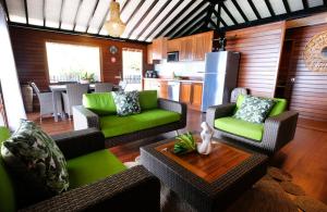 a living room with green furniture and a kitchen at Bungalow N°1 Temae Beach by Enjoy villas in Moorea