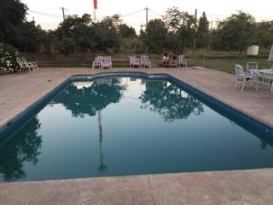 a swimming pool with chairs and a table and a person sitting at Casa de Campo en Malloco in Peñaflor