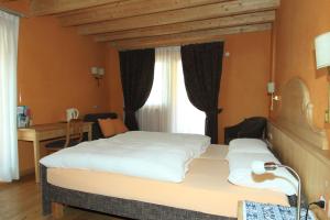 a bedroom with a bed and a desk and a window at Bio Hotel Villa Cecilia in Livigno