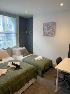 倫敦的住宿－Comfy Private Bedrooms near Euston, Central London (127)，客房设有两张床、一张桌子和一张书桌。