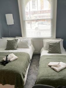 2 Betten neben einem Fenster in einem Zimmer in der Unterkunft Comfy Private Bedrooms near Euston, Central London (127) in London