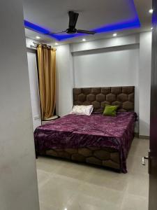 a bedroom with a large bed with a purple blanket at exclusive apartment for bash in Faridabad