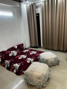 a bedroom with a bed and two ottomans at exclusive apartment for bash in Faridabad
