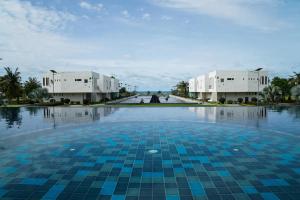 a swimming pool with blue tiles in front of buildings at Serene Phla Resort and Restaurant in Rayong