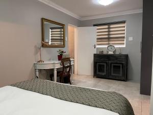 1 dormitorio con cama, lavabo y escritorio en Hill Luxury Cottage, en Roodepoort