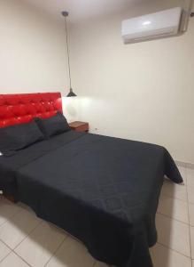 um quarto com uma cama preta e uma cabeceira vermelha em Apartamento céntrico Frida's todo nuevo em Tarija