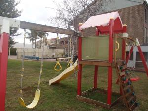een speeltuin met een glijbaan en schommels bij City Colonial Motor Inn in Mildura