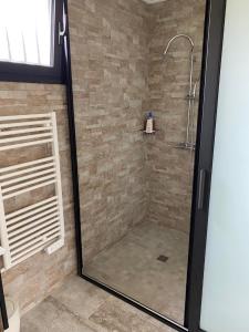 La salle de bains est pourvue d'une douche avec une porte en verre. dans l'établissement Les Villas de Bella, à Saint-Louis