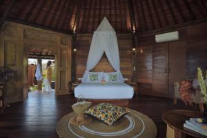 1 dormitorio con 1 cama en una habitación con mesa en Wasita Eco Villa Ubud, en Ubud