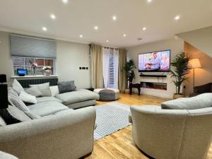 sala de estar con sofás y TV de pantalla plana. en Entire house with a large lounge en Leverstock Green