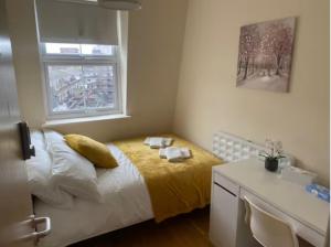 ein Schlafzimmer mit einem Bett mit gelber Bettwäsche und einem Fenster in der Unterkunft Private Rooms in Euston Square, Central London (161/4) in London