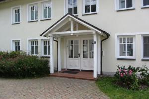 una casa bianca con una porta e un portico di Dünenpark Binz - Düne 11 Apartment 89 a Binz