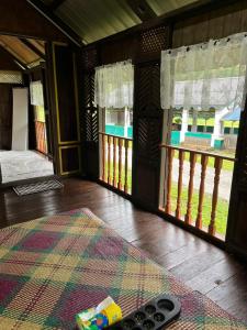 Zimmer mit einem Bett, einem Teppich und Fenstern in der Unterkunft Kampung House (Minang) in Hulu Yam, Batang Kali in Batang Kali