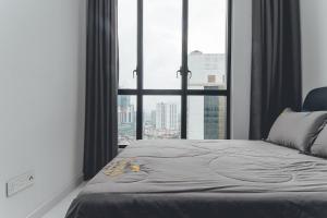 Bett in einem Zimmer mit einem großen Fenster in der Unterkunft Sky88 High-rise Cozy Stay 2BR nr CIQ/KSL/Midvalley by Our Stay in Johor Bahru