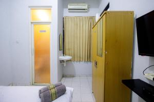 La salle de bains est pourvue d'une porte jaune et d'un lavabo. dans l'établissement Marcello Residence Siwalankerto near Petra University Surabaya Mitra RedDoorz, à Surabaya