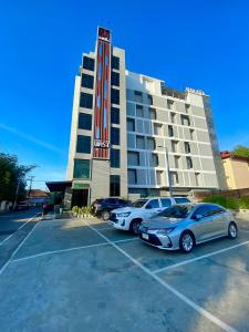 a hotel with three cars parked in a parking lot at Nakara Hotel, Ubon Ratchathani in Ban Na Kham