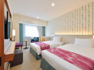 那覇市にあるホテルJALシティ那覇のベッド2台とテレビが備わるホテルルームです。