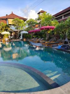 a large swimming pool with chairs and umbrellas at Berlian Inn Kuta Beach in Kuta