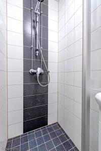 een badkamer met een douche met zwarte en witte tegels bij Valoisa & Mukava koti vallilassa in Helsinki