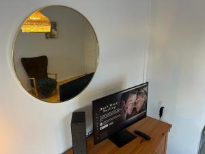een spiegel aan een muur met een televisie op een bureau bij Valoisa & Mukava koti vallilassa in Helsinki