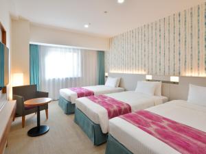 a hotel room with two beds and a table at Hotel JAL City Naha in Naha