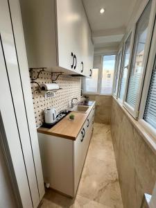 uma pequena cozinha com armários brancos e um lavatório em Garsoniera SARA em Târgu Jiu