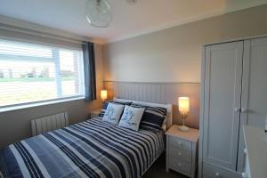 a bedroom with a bed with pillows and a window at Driftwood Heart in Freshwater