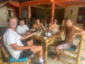 a group of men sitting at a table eating food at SuperSuck Hotel in Maluk