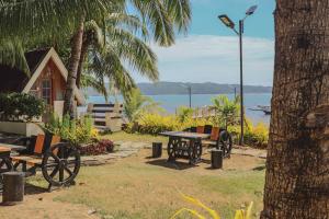 a picnic table and benches in front of a house at Southdrive Beach Resort in Bulalakao