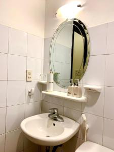 Baño blanco con lavabo y espejo en Tran Ly Hotel, en Hue