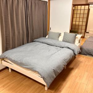 a bedroom with a bed with a gray blanket at 空港＆海遊館直通、2WAYアクセス便利、過客ノ家ー弁天町 in Osaka