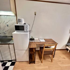 a kitchen with a table and a microwave on top of a refrigerator at 空港＆海遊館直通、2WAYアクセス便利、過客ノ家ー弁天町 in Osaka