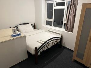 a small bedroom with a bed and a window at Tran UK Homestay in London