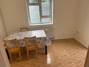 een eetkamer met een tafel en stoelen en een raam bij Tran UK Homestay in Londen