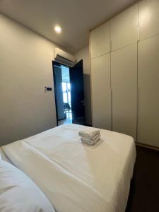 1 dormitorio con 1 cama blanca y 2 toallas en Opus Residences Warisan PNB 118 View, en Kuala Lumpur