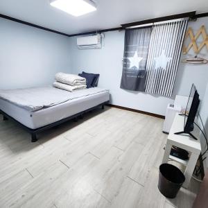 um quarto com uma cama e uma televisão em Yeobyeol Guesthouse em Jeonju