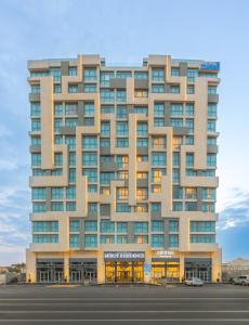 um edifício alto com um parque de estacionamento em frente em فندق ميروت-Mirot Hotel em Al Khobar