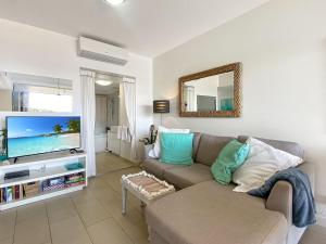 a living room with a couch and a flat screen tv at 1 Bright Point Apartment 3104 in Nelly Bay