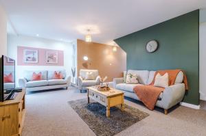 a living room with two couches and a clock on the wall at Beautiful House near Etihad with Free WiFi & Parking- Sleeps 6 by PureStay in Manchester