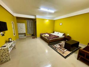 ein Schlafzimmer mit einem Bett und einer gelben Wand in der Unterkunft Hotel Vivid Tawang in Tawang