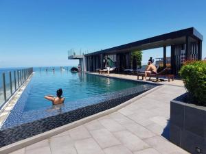a woman sitting in a swimming pool next to the ocean at The Base Central Pattaya by Leya in Pattaya Central