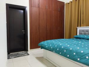 BEAUTIFUL VACATION HOME AT DUBAI BY MAUON TOURISM في دبي: غرفة نوم بسرير من الشراشف الزرقاء والخزائن الخشبية